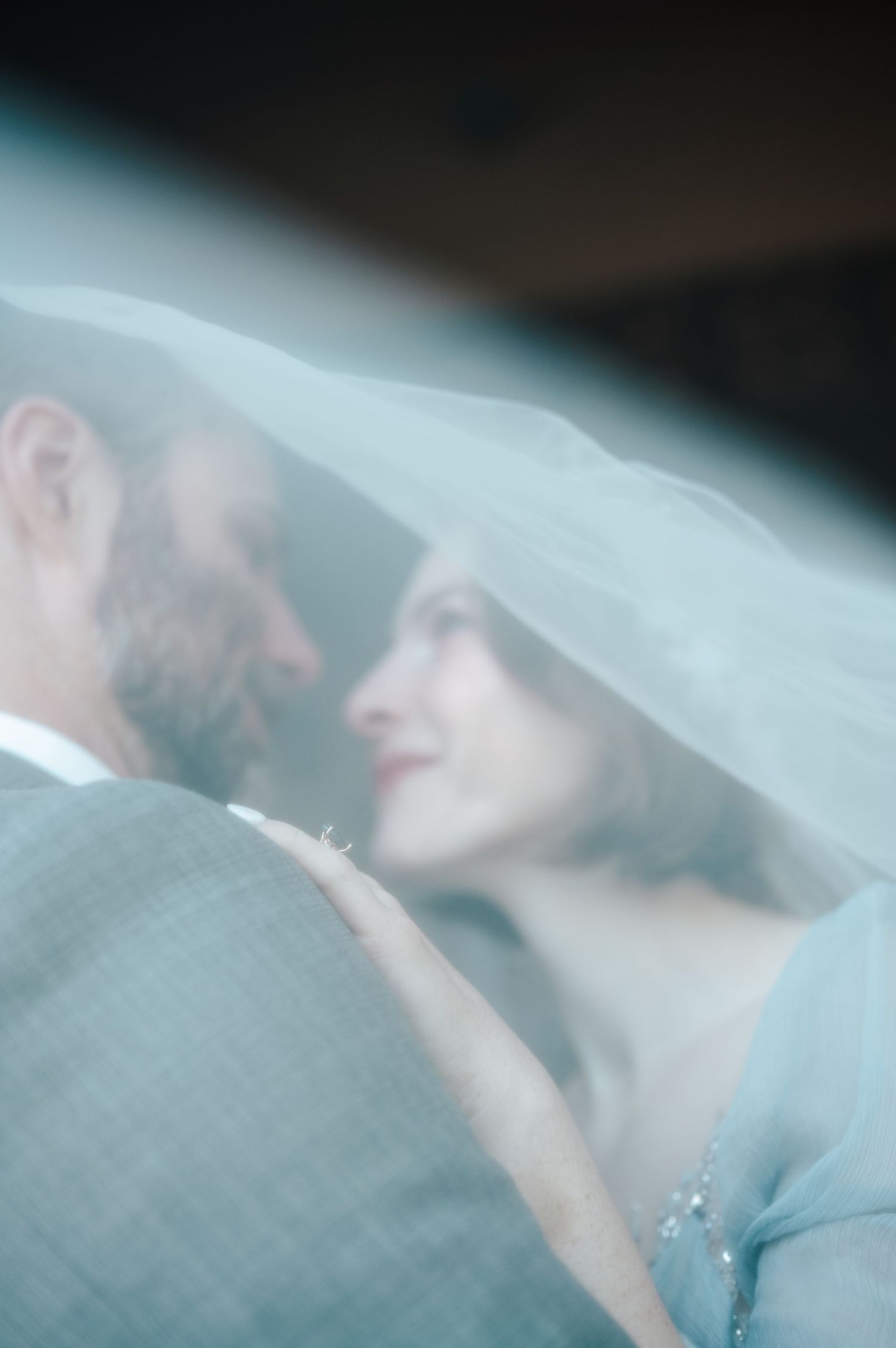 A romantic wedding moment captured through a soft veil with a dreamy, ethereal quality.