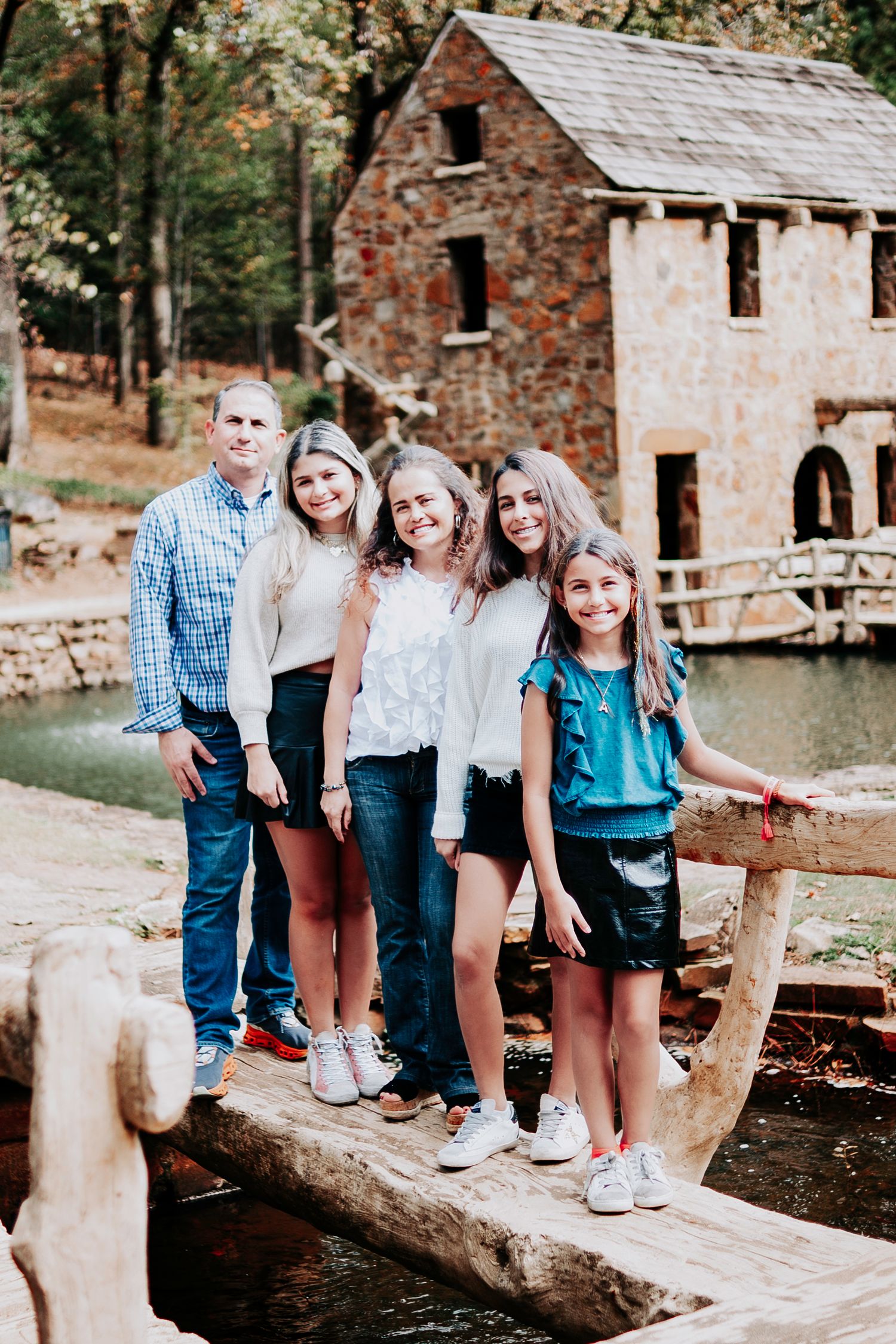 Group sitting on rustic wooden bridge near historic stone building.