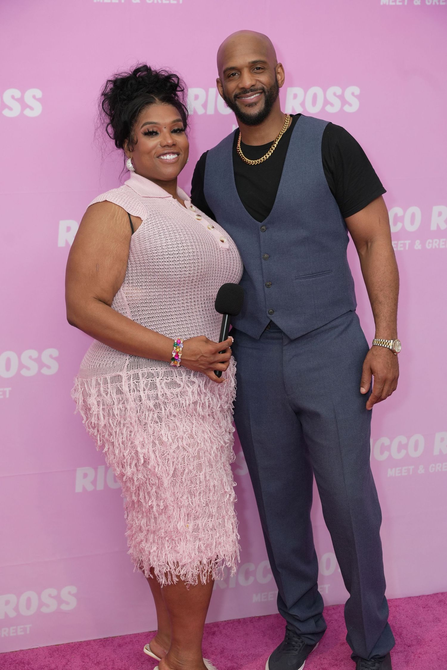 Media outlet and George Middlebrook posing together at a Ricco Ross meet and greet event, woman in pink fringe dress, man in gray vest.