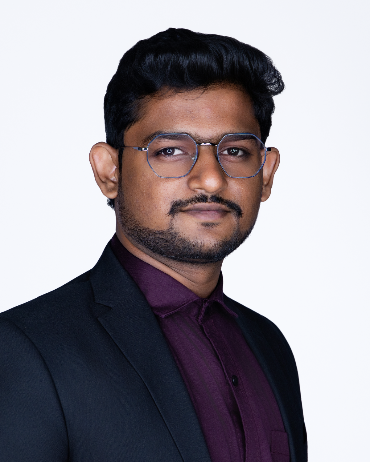 Professional headshot of a young man wearing glasses, a dark suit, and burgundy shirt with tie against white background.