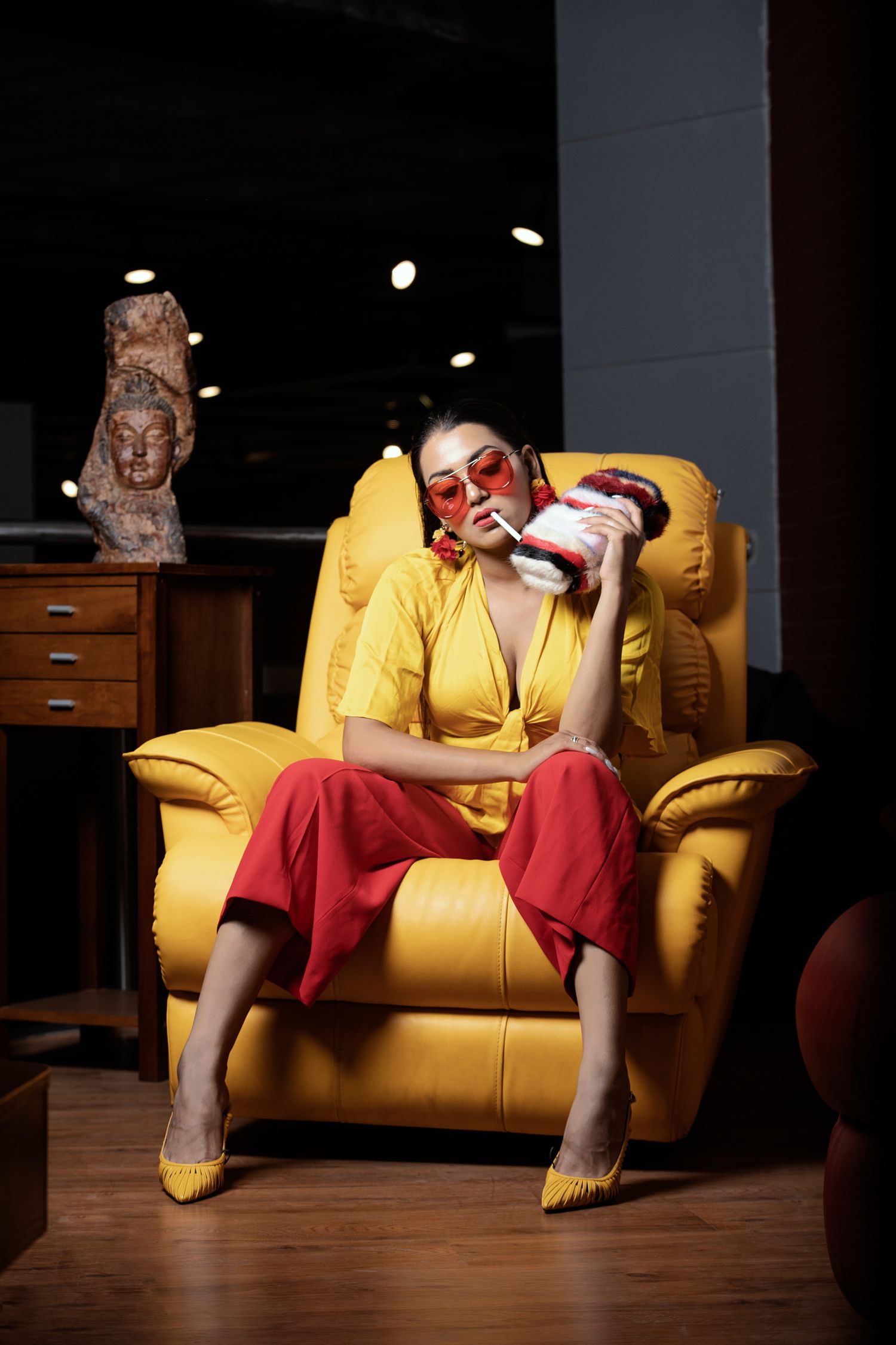 Artistic portrait on yellow leather couch with dramatic lighting and theatrical makeup.