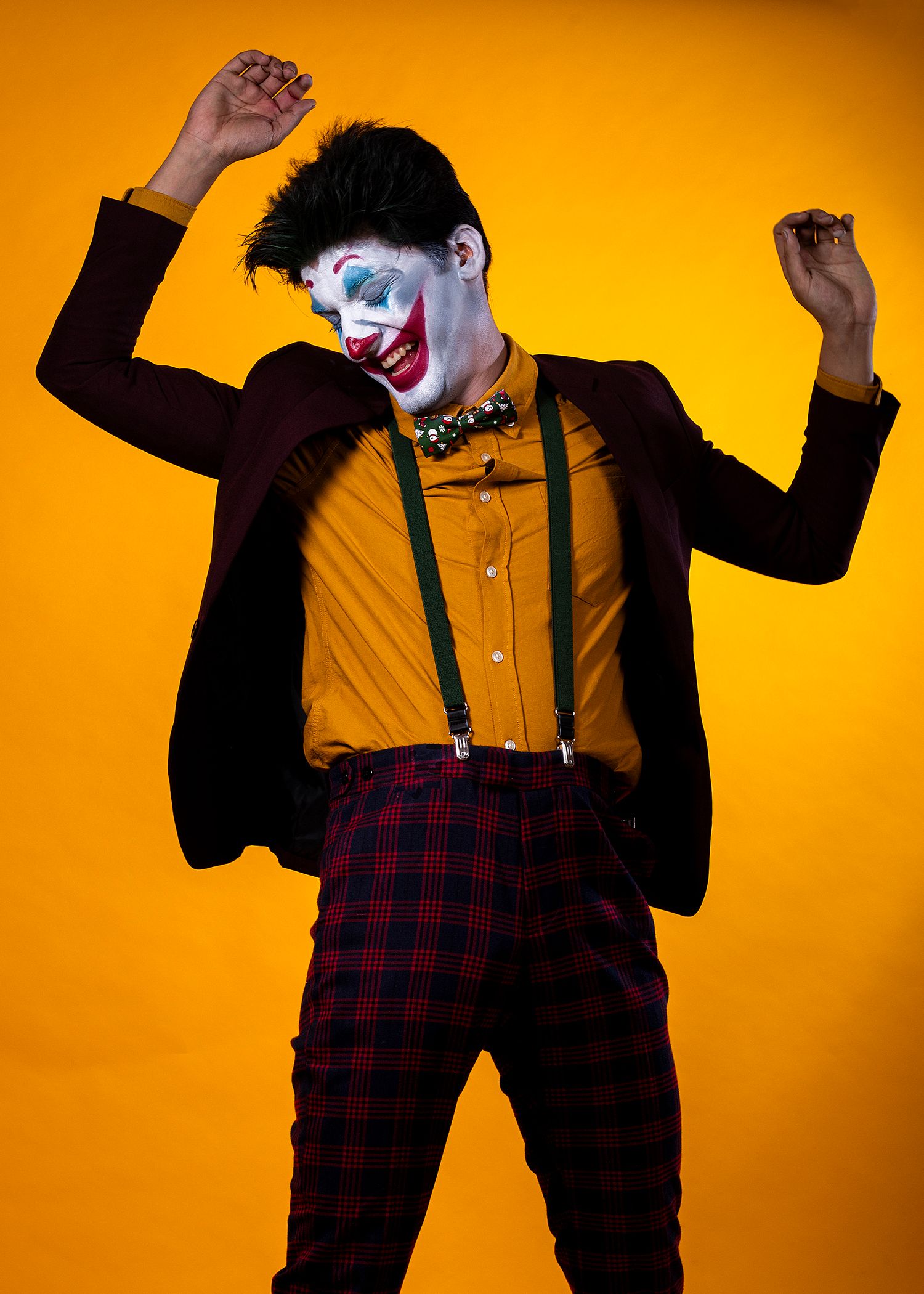 Energetic poses against vibrant orange background showing figure in plaid pants and suspenders.