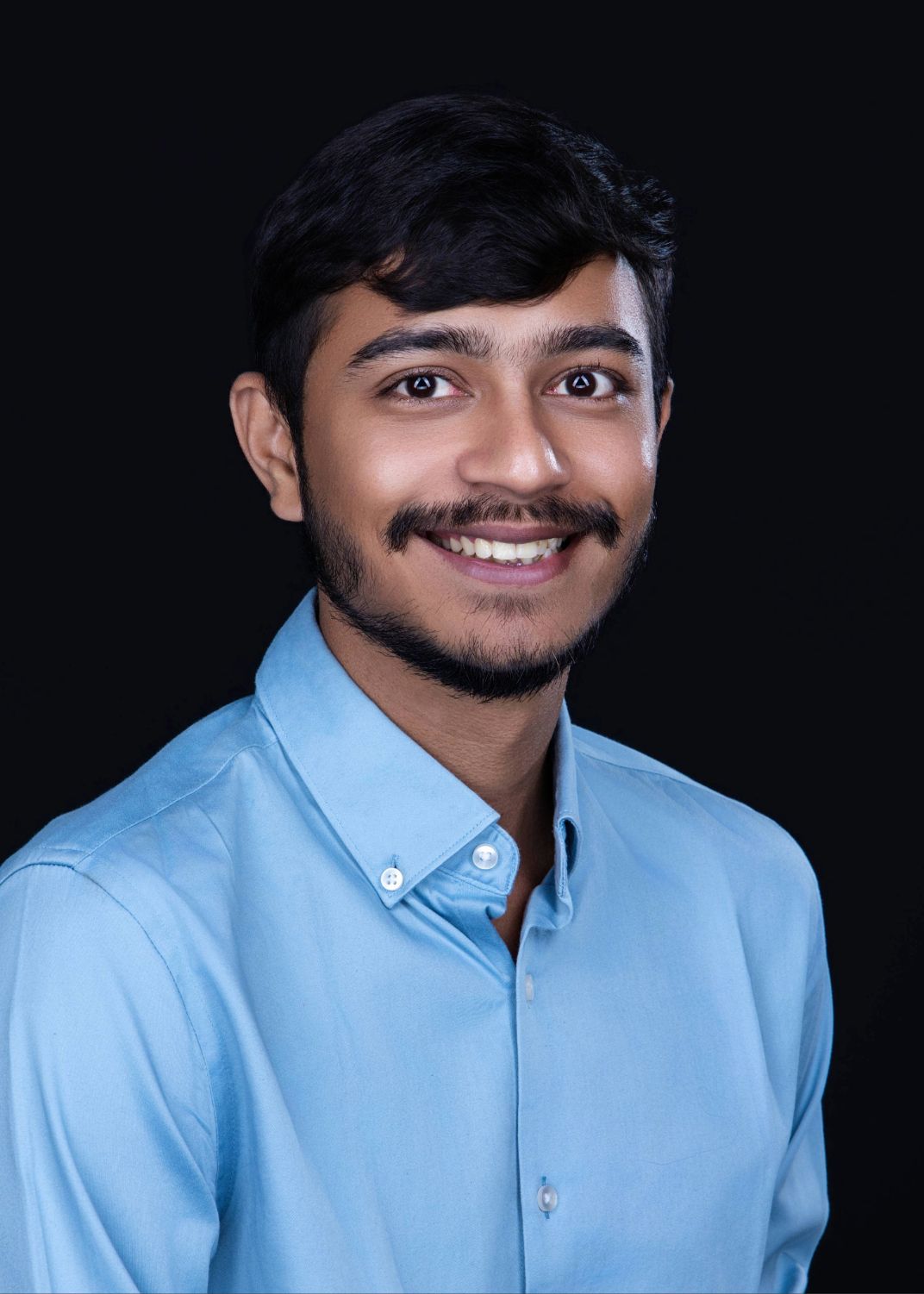 A person wearing a light blue button-down shirt poses against a dark background in a series of photos.