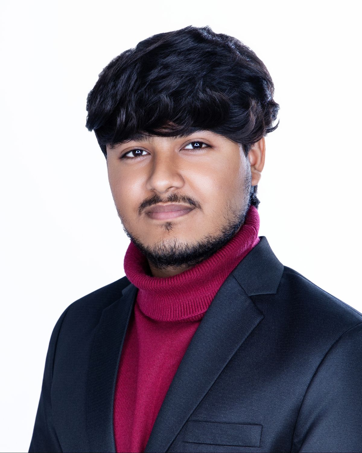 Young man in a dark blazer and red turtleneck sweater posing for a professional portrait photo.
