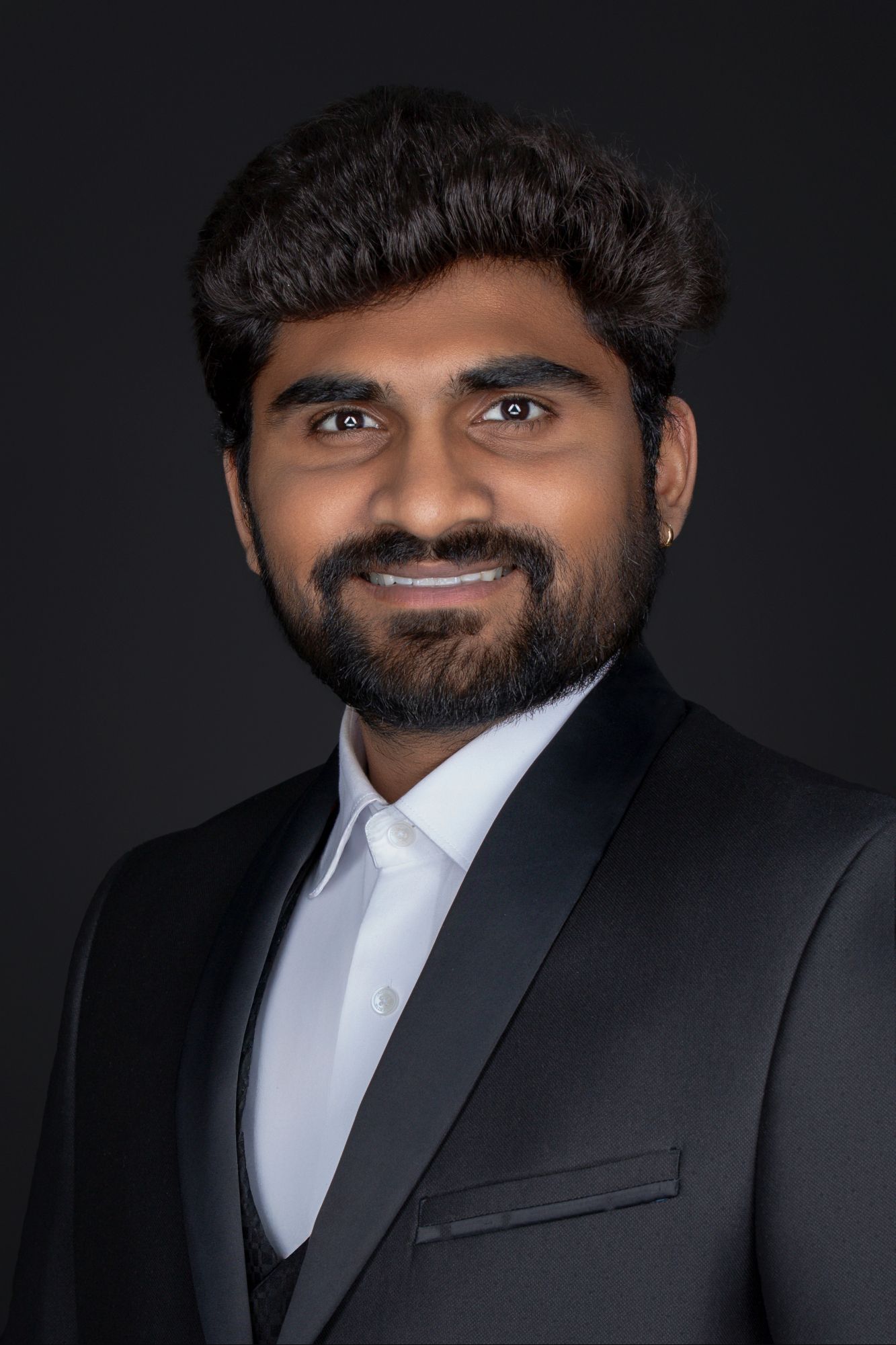 Portrait series of person in black suit showing different angles against dark backdrop.