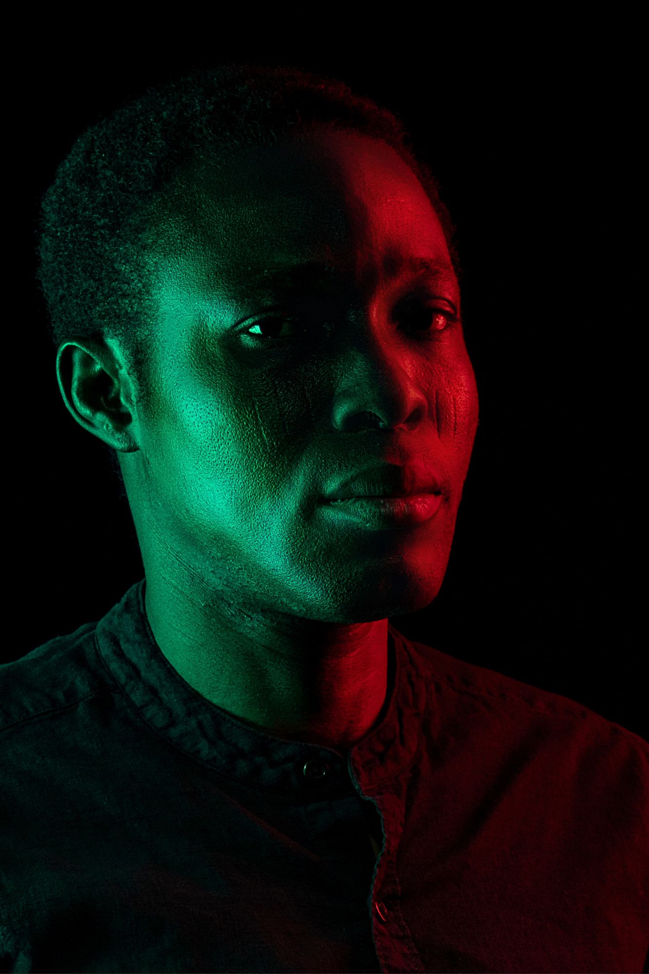 Dramatic portrait with split lighting using red and green colored gels creating contrasting shadows and highlights.