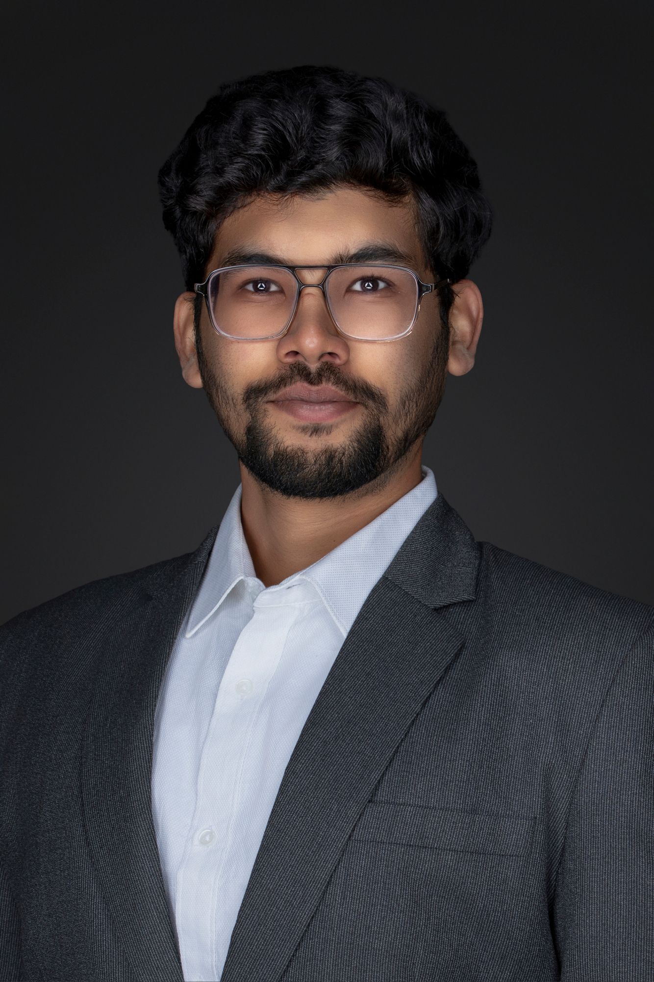 Business portrait of person wearing glasses, grey suit and white shirt.
