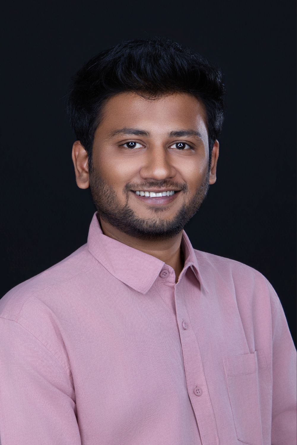 Professional headshot of someone wearing a light pink collared shirt against a dark background.