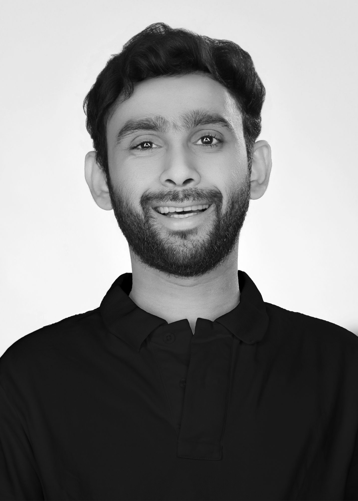 Black and white portrait of a bearded man in a dark shirt smiling warmly at the camera.