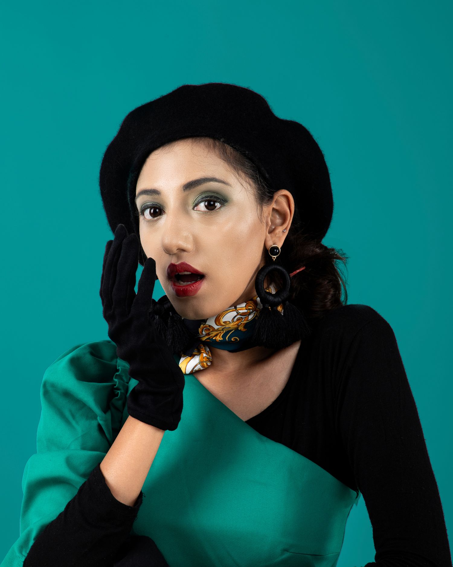 Dramatic fashion portrait with red lipstick and black gloves against teal background.