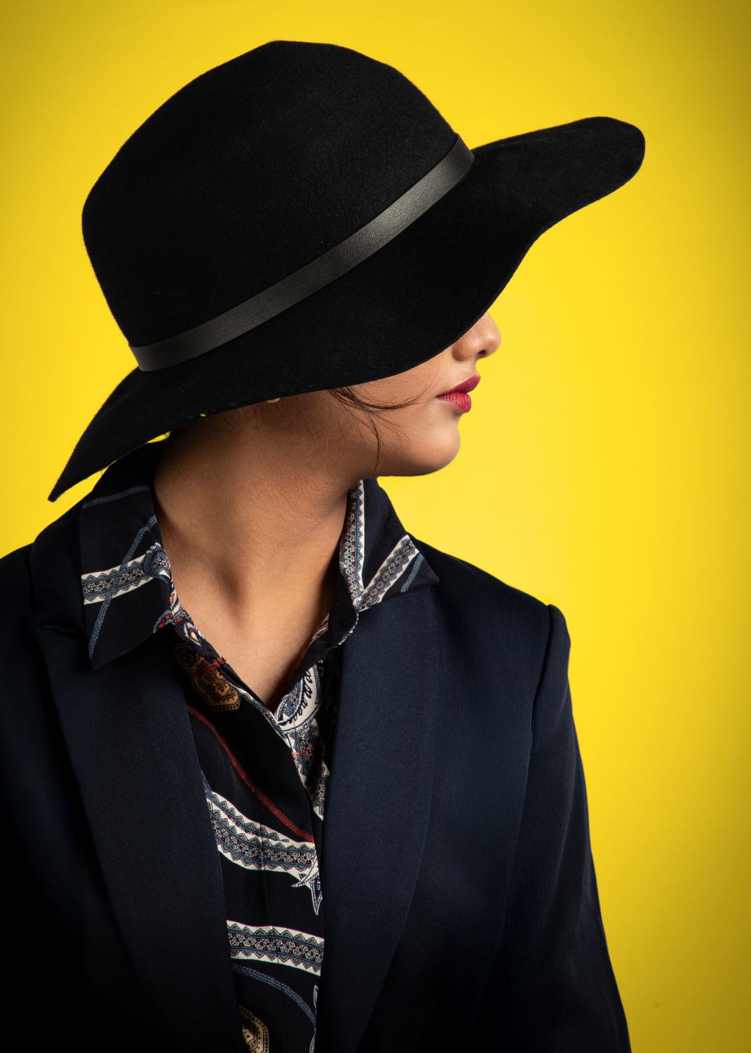 Stylish fashion portraits with black hat and blazer against bright yellow background.