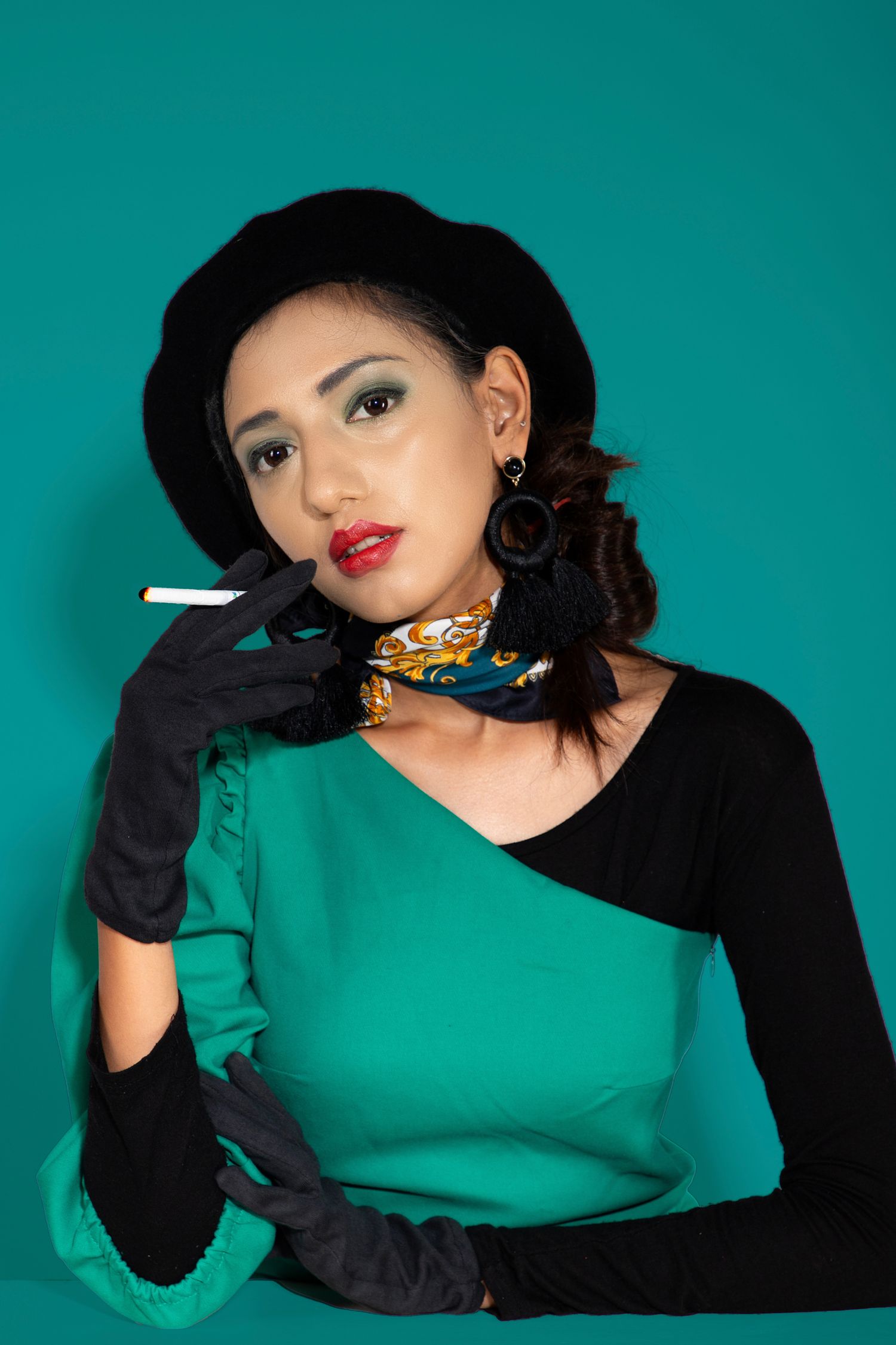 Glamorous vintage-style portraits with emerald green background and black gloves.