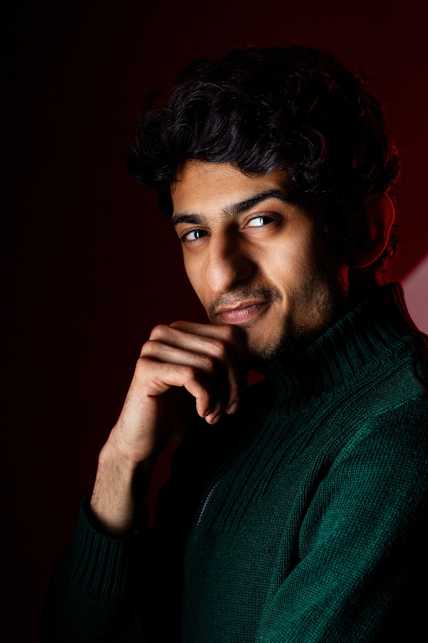 Expressive portrait series in green turtleneck against dark red background.