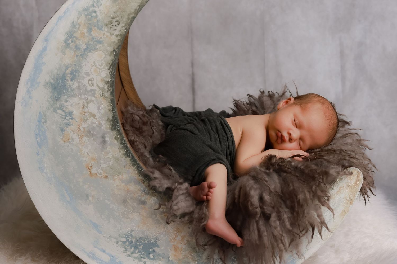 A sleeping baby lies peacefully in a vintage-style bathtub with blue floral pattern details. luxury-family-photography-Rancho