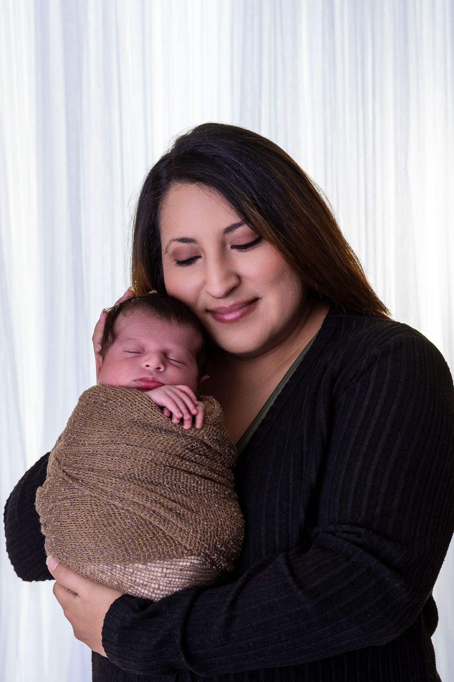 A series of tender moments showing a parent holding and cuddling a swaddled newborn baby in brown fabric. luxury-family-photography-Azusa