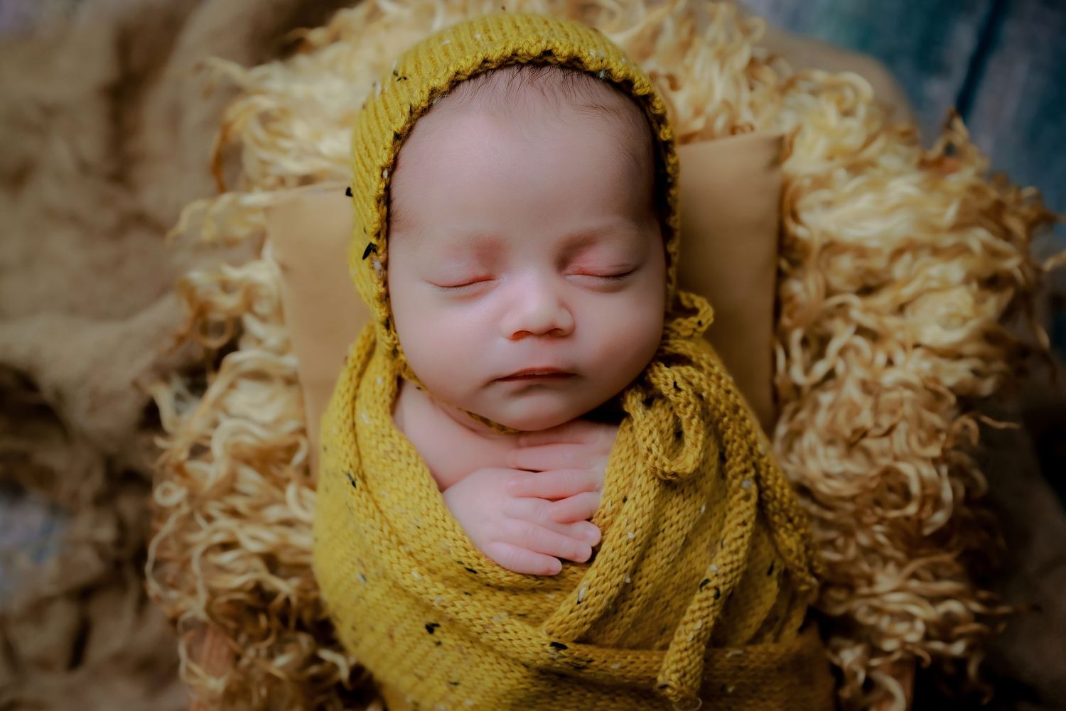Peaceful sleeping newborn wrapped in soft yellow knit swaddle on cream textured blanket. luxury-family-photography-Irwindale
