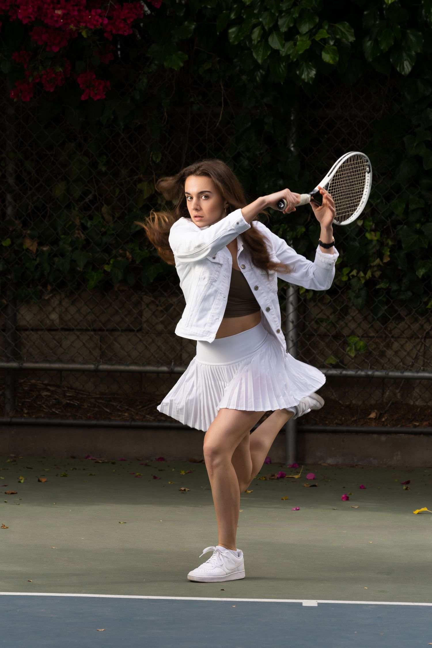 Tennis player in white dress and shoes performs graceful spinning motion sequence on outdoor court.