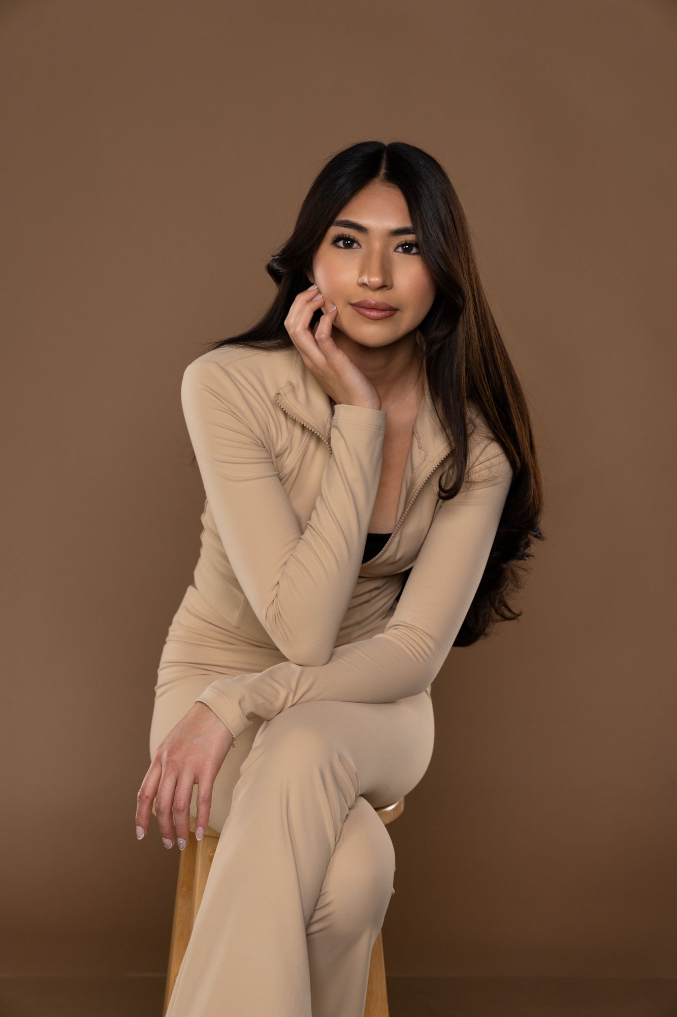 Professional studio portrait of a person in beige suit posing against brown mocha background in four different poses.
