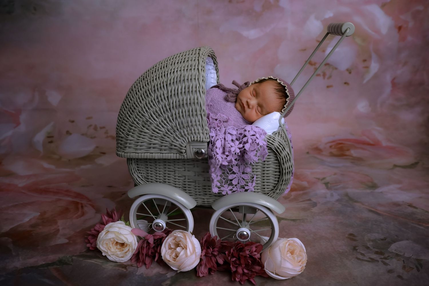 Vintage wicker baby carriage with pink roses and floral decorations against a pink backdrop. luxury-family-photography-fontana