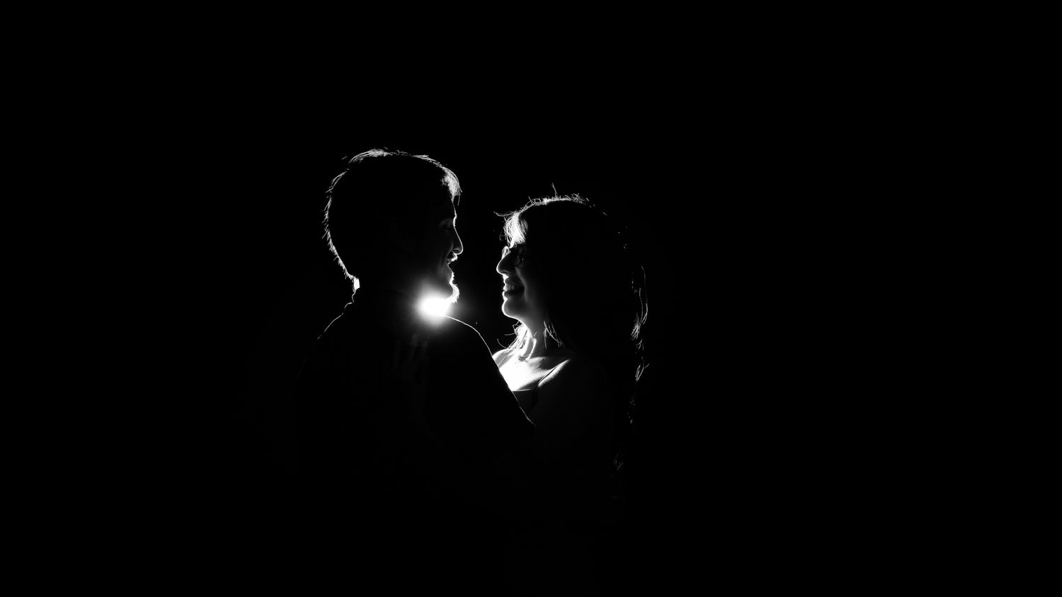 silhouette photo of a couple on black and white holding each other looking into each others eyes lovingly
