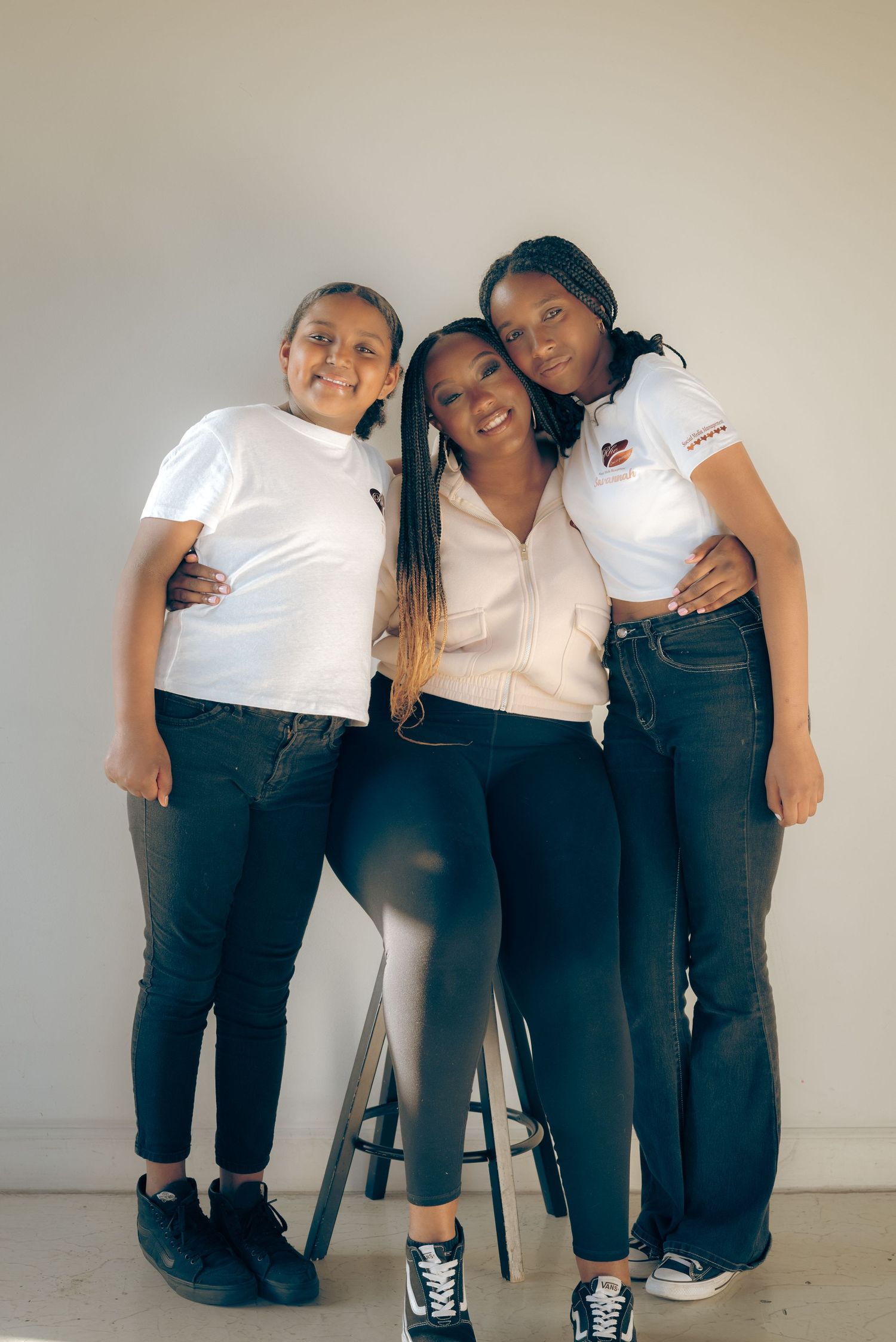Three friends in white tops and dark pants pose together in a playful series of casual group photos against a light background.