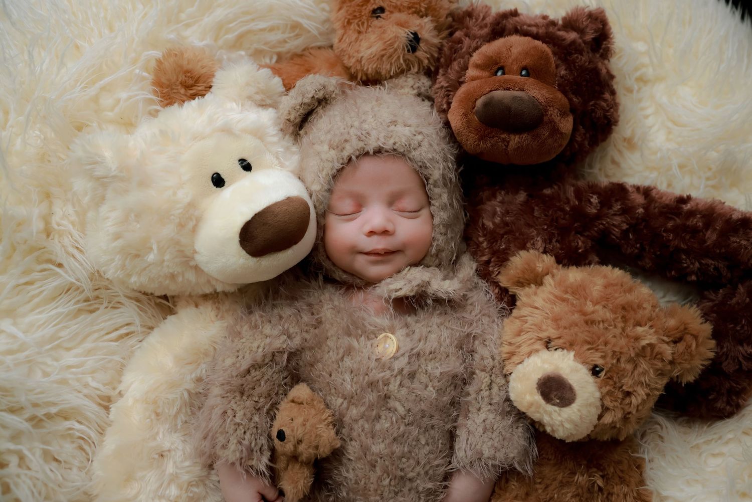 A cozy scene with plush teddy bears arranged on soft white fur with a small figure in a fuzzy brown outfit. luxury-family-photography-upland
