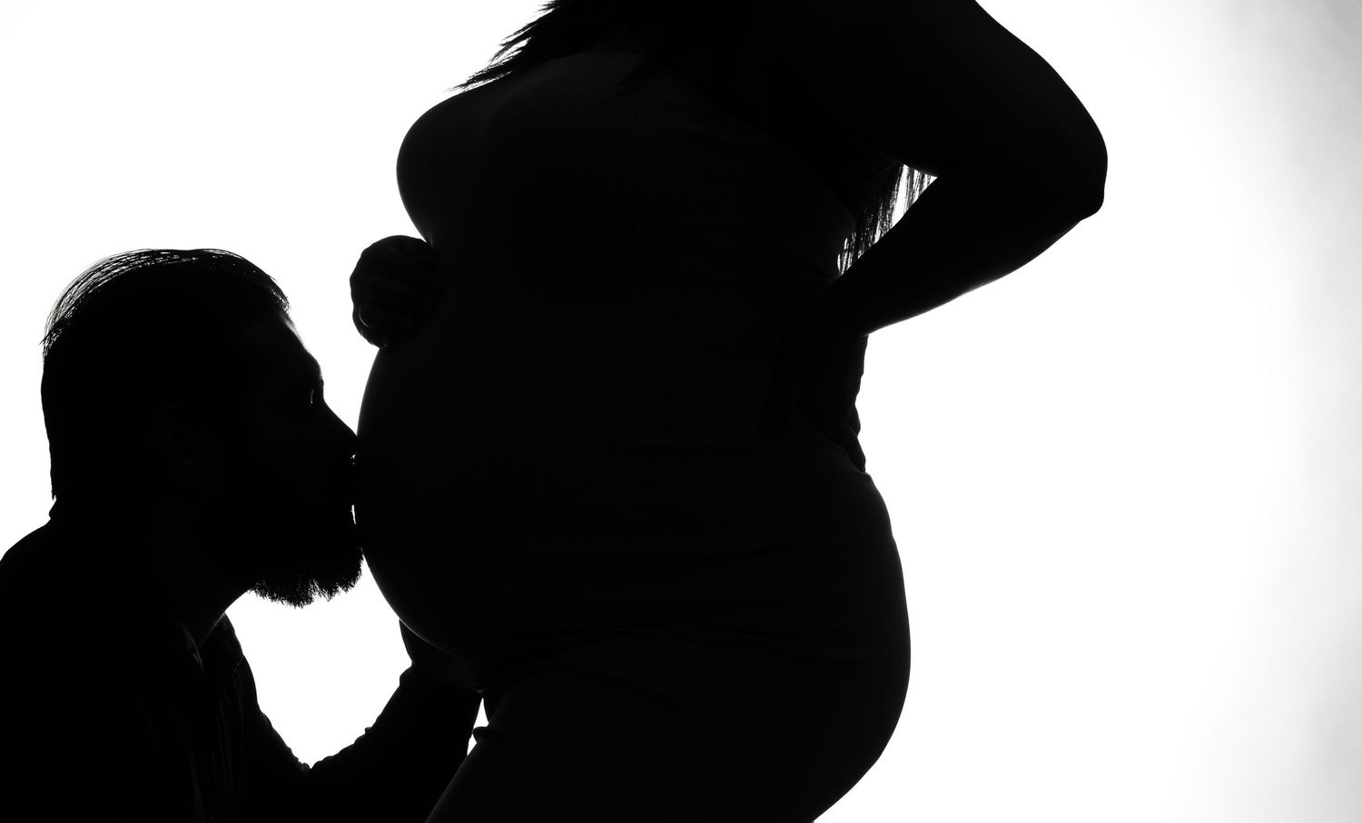 A silhouetted figure stands in a dramatic pose against a bright white background.