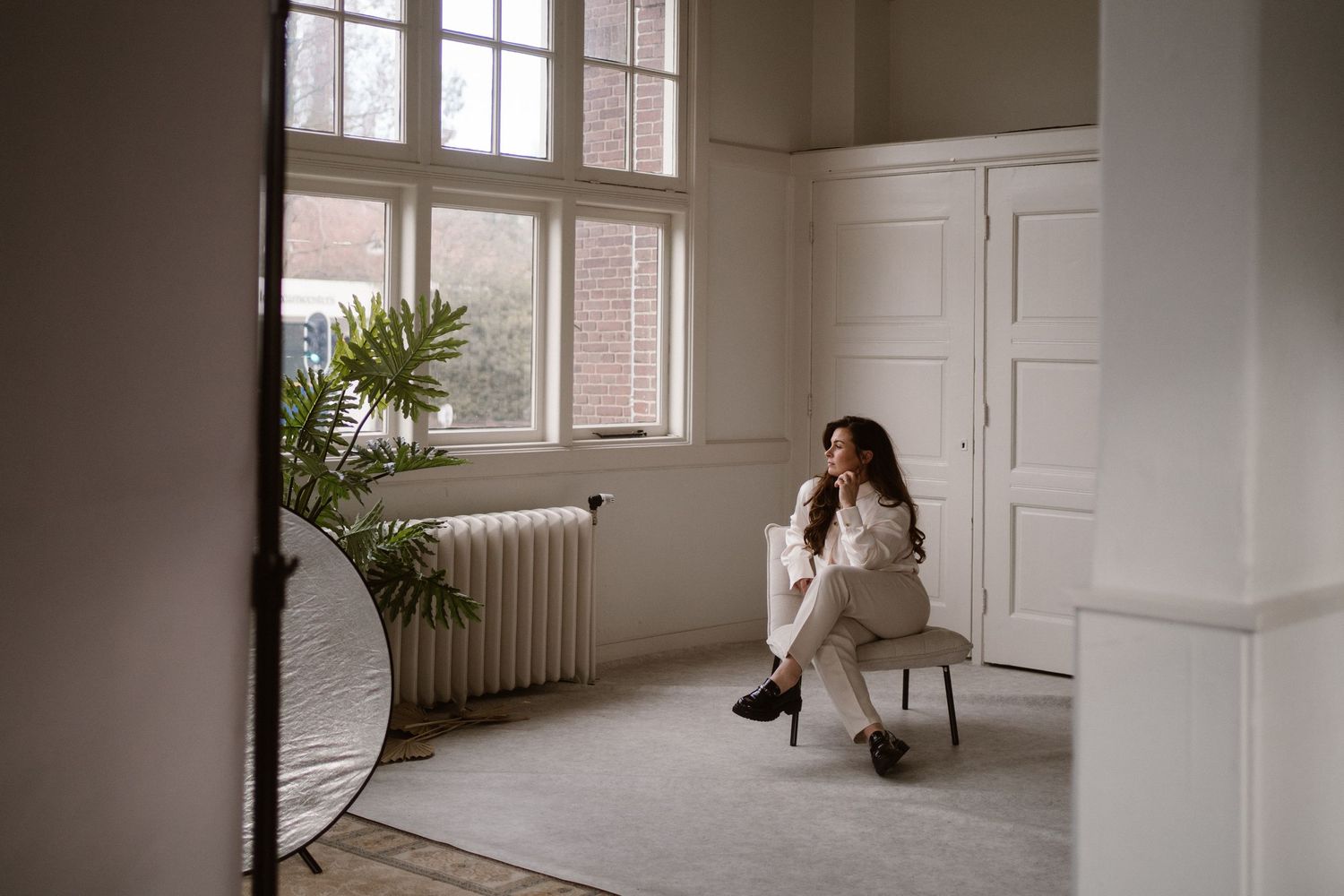 Empty white room with large windows and natural light streaming in.