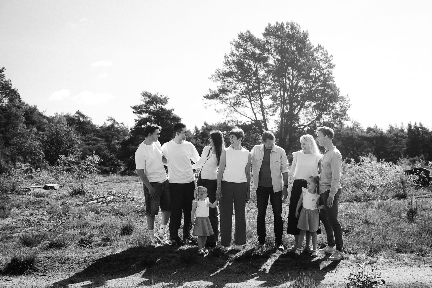 Black and white photo of a large family group standing together outdoors in a natural landscape with trees.