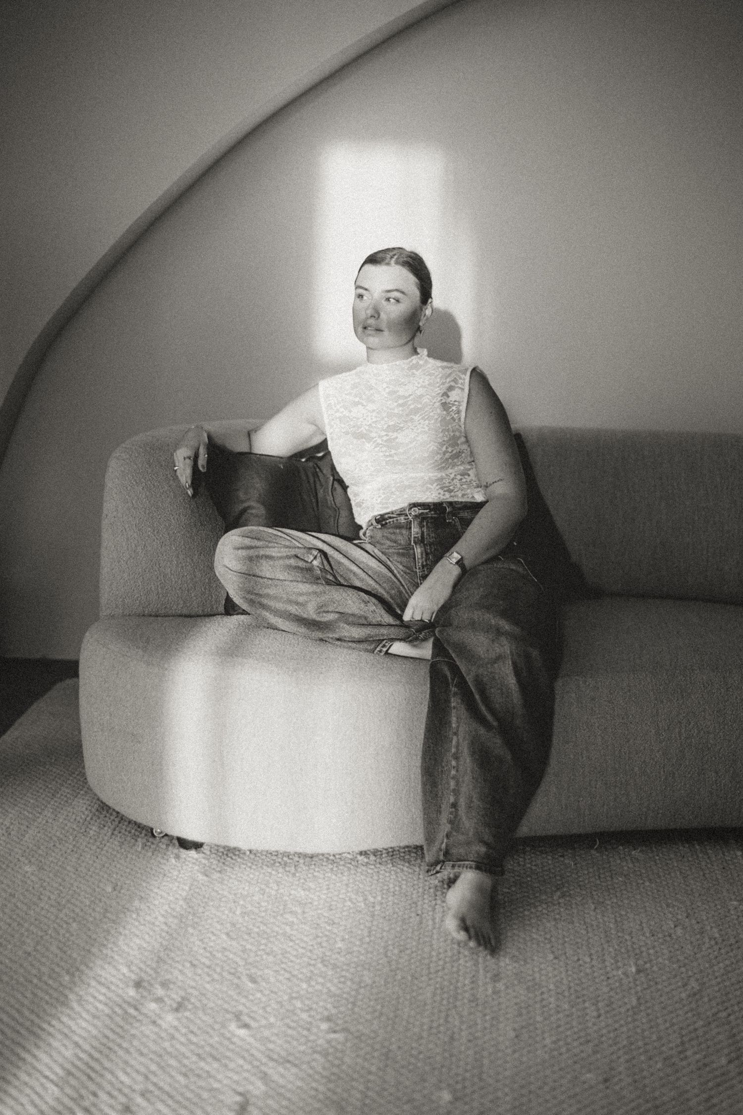 Black and white series showing relaxed poses on a curved modern sofa.