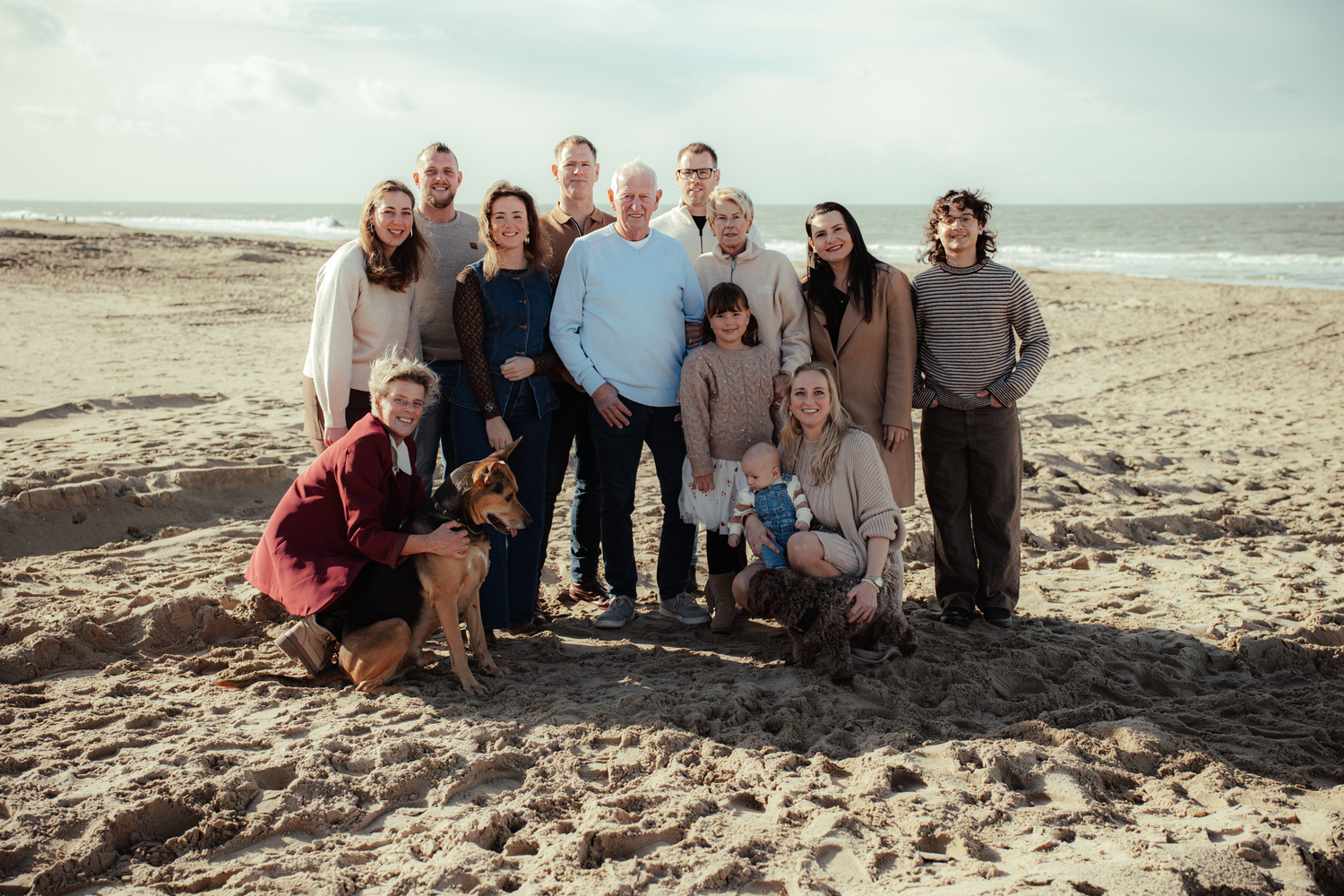 Extended family gathering for group photos on a sandy beach.