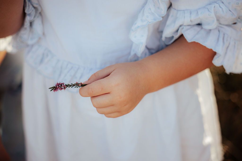 Close-up detail of white eyelet dress against natural outdoor setting.
