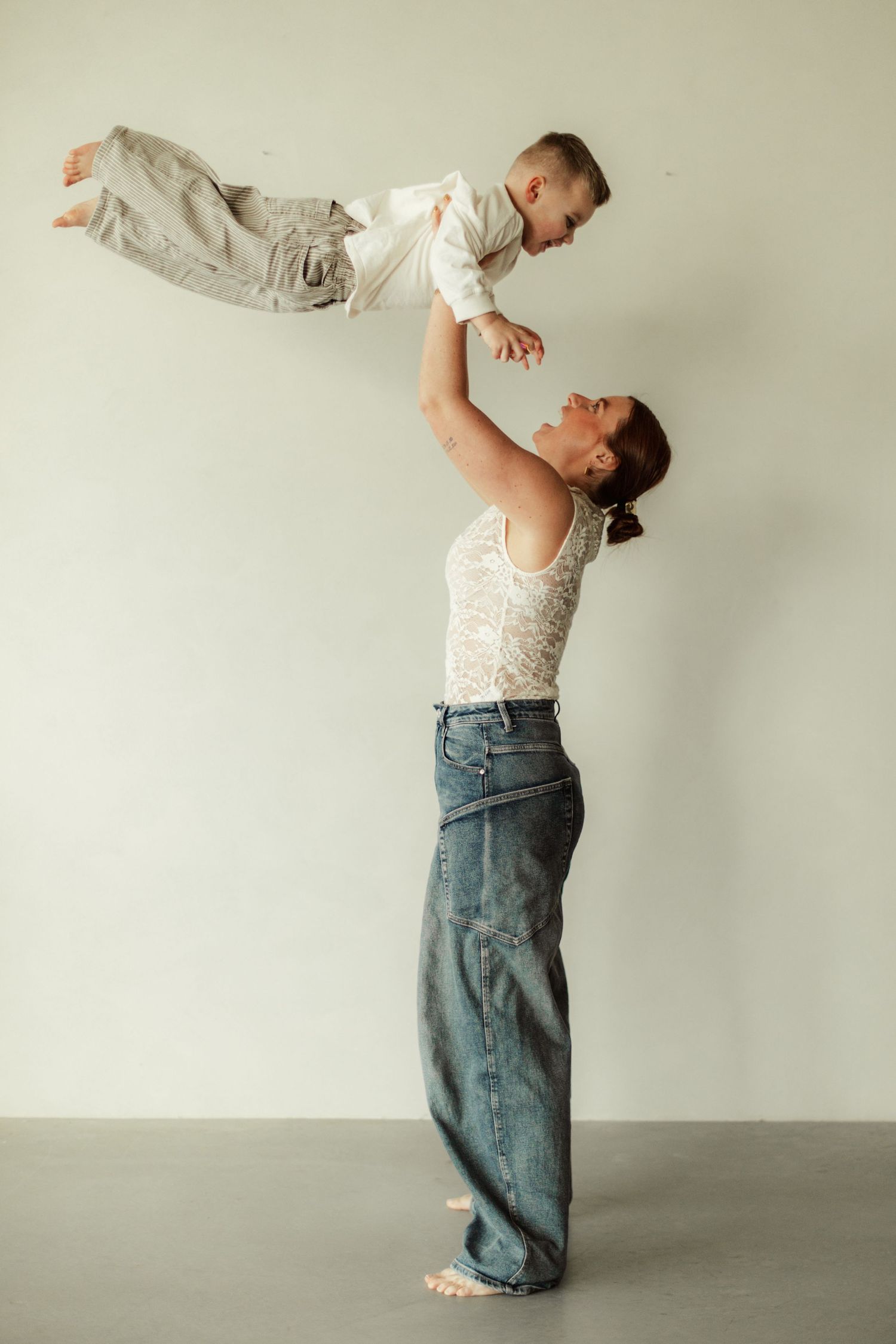 Joyful moment captured as parent lifts child high in studio setting.