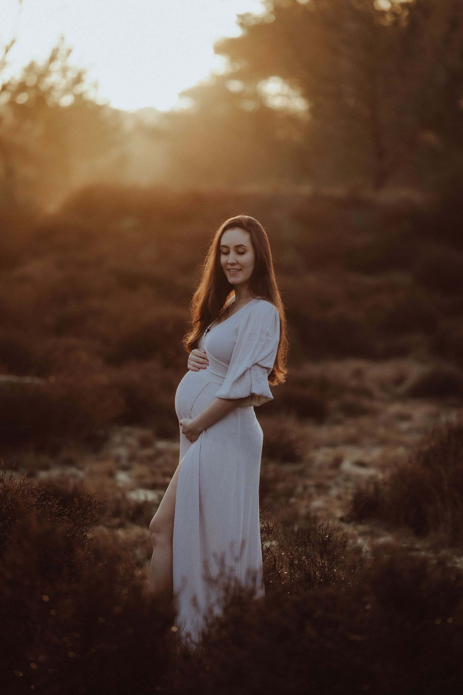 Artistic maternity photos captured during golden hour in natural outdoor setting.