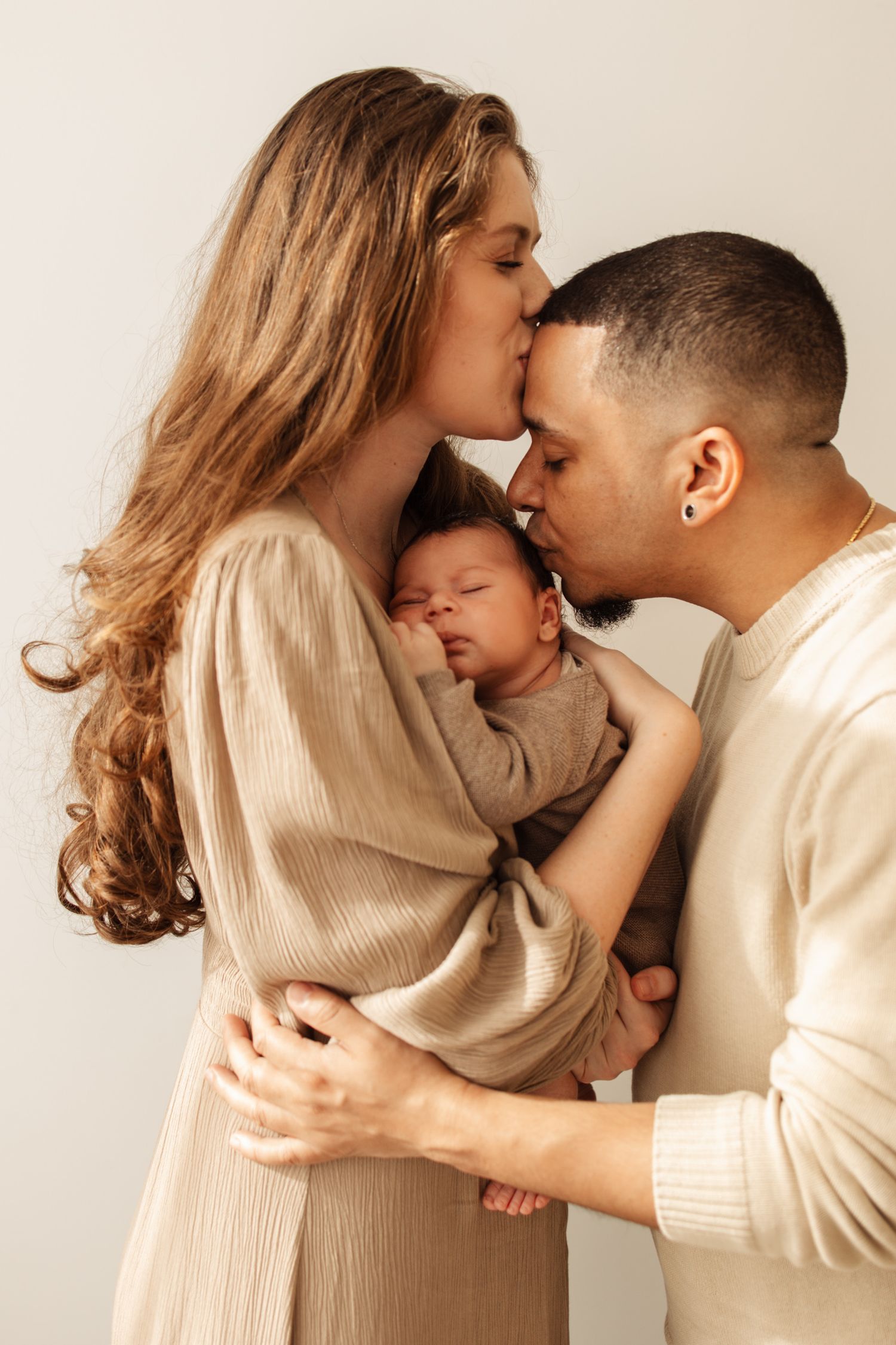 Family sharing intimate moment together against neutral background.