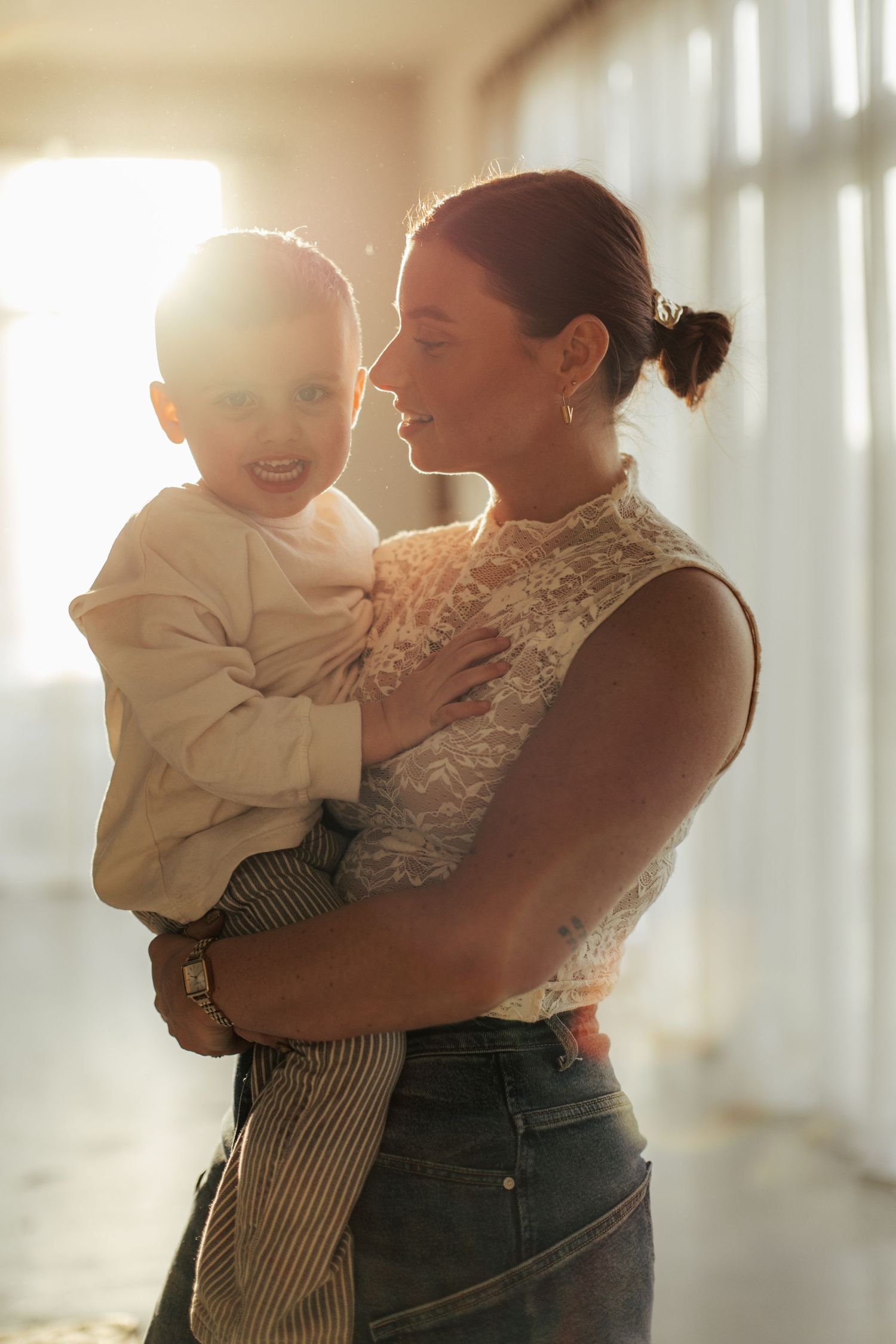 Tender moment between parent and child backlit by soft window light.