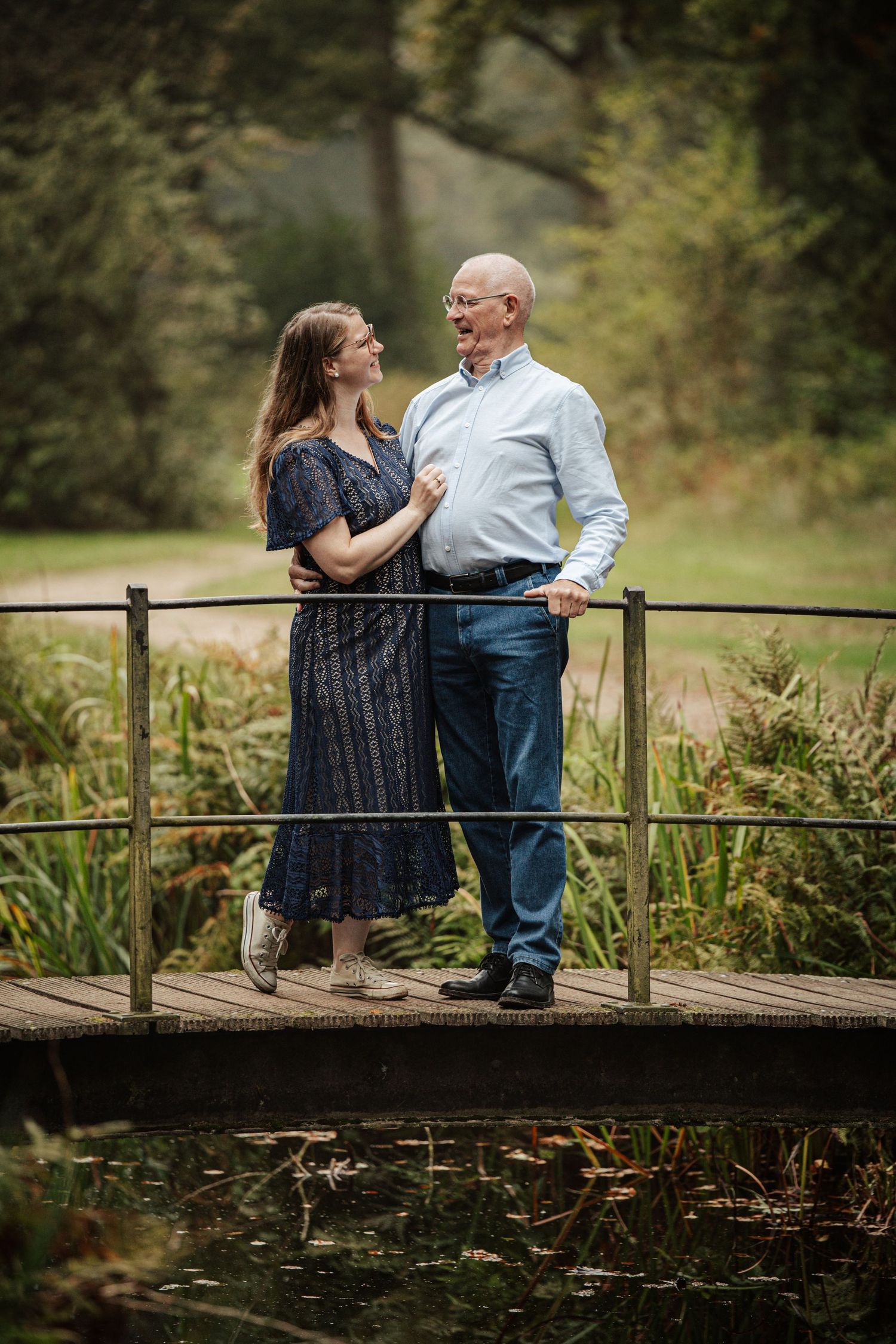 Couple sharing romantic moment on wooden bridge over pond.