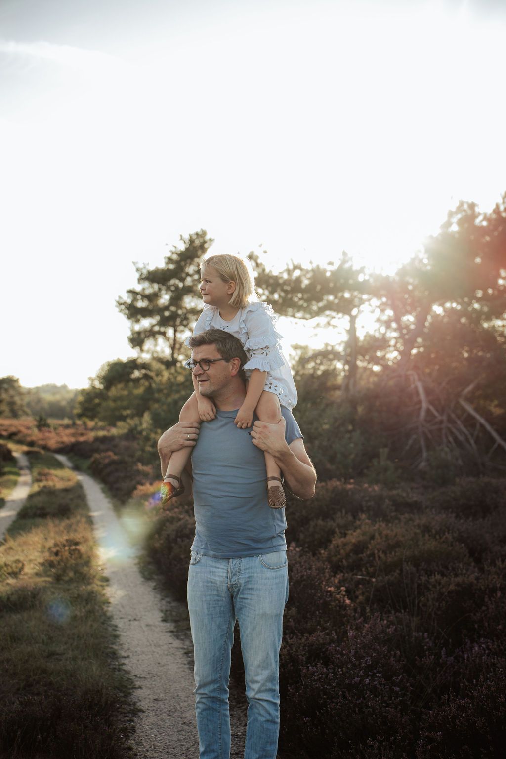 Family enjoying a sunset walk together on a nature trail with blooming heather.