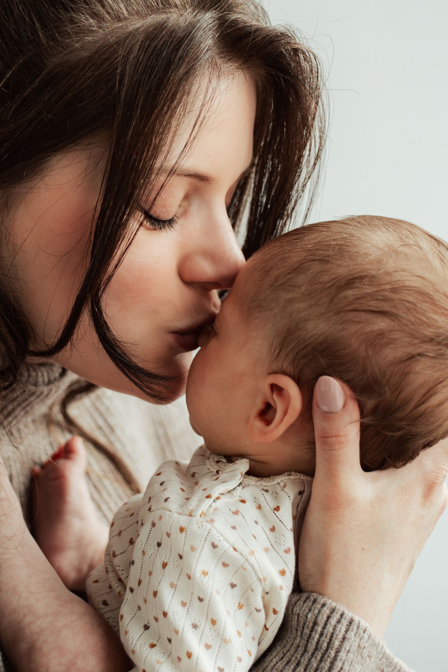 Intimate black and white portraits showing gentle maternal moments with an infant.