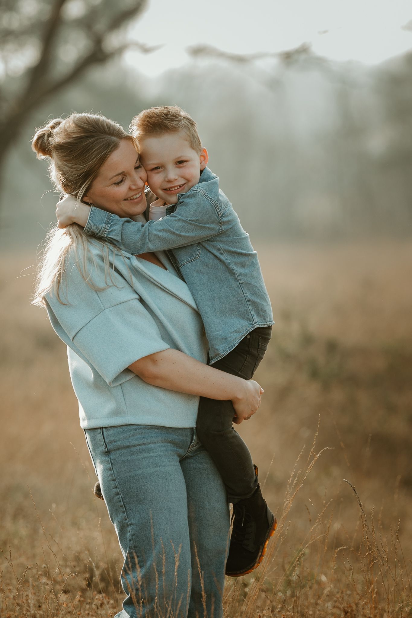 Joyful outdoor portrait showing warm family embrace in matching blue outfits.
