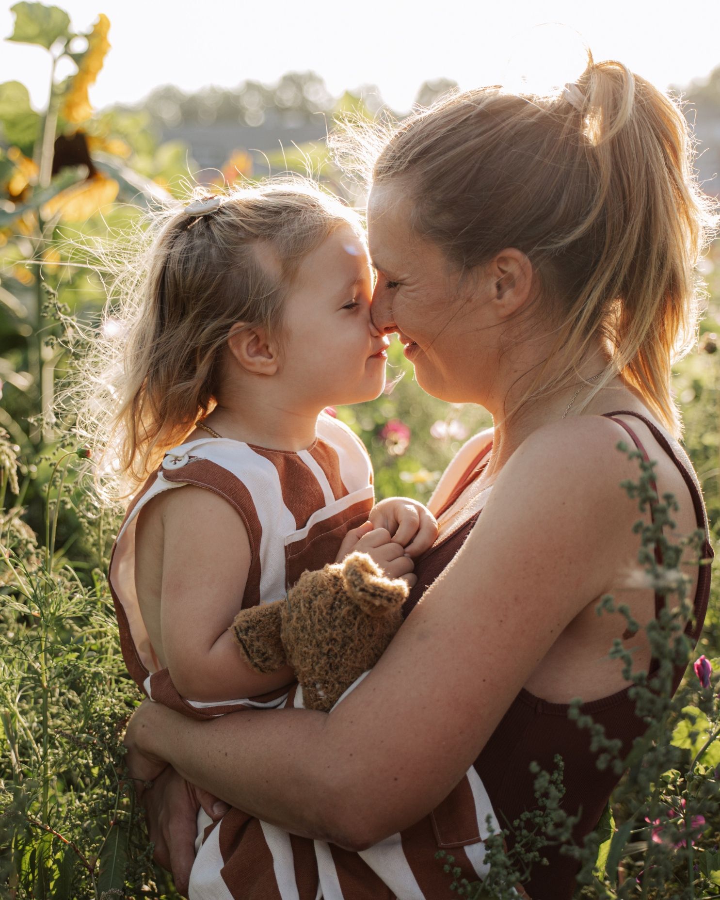 Tender outdoor portrait sequence captured in golden sunlight among flowers and greenery.