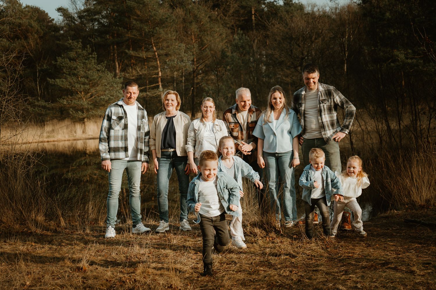Extended family posed together on a hillside during sunset.