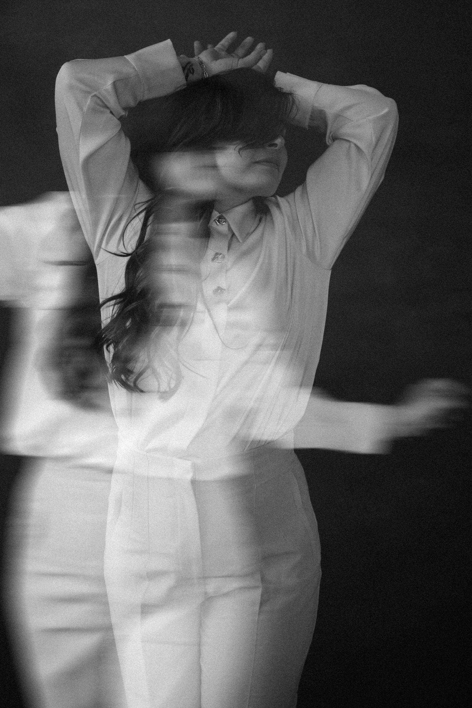 Abstract black and white motion sequence showing a figure in white clothing against dark background.