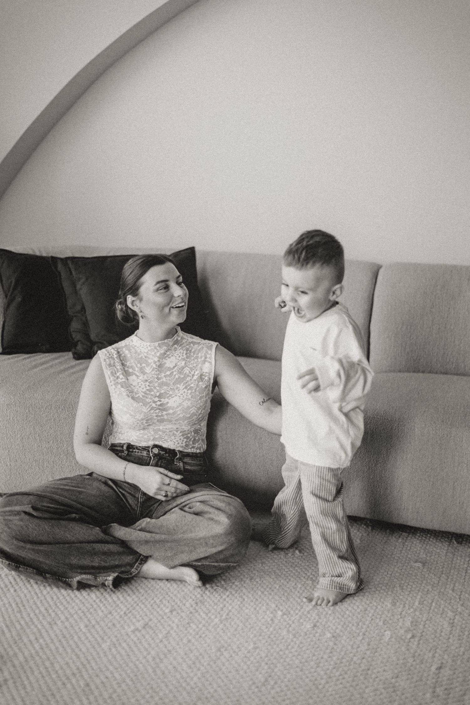 Black and white candid moment between parent and child on couch.