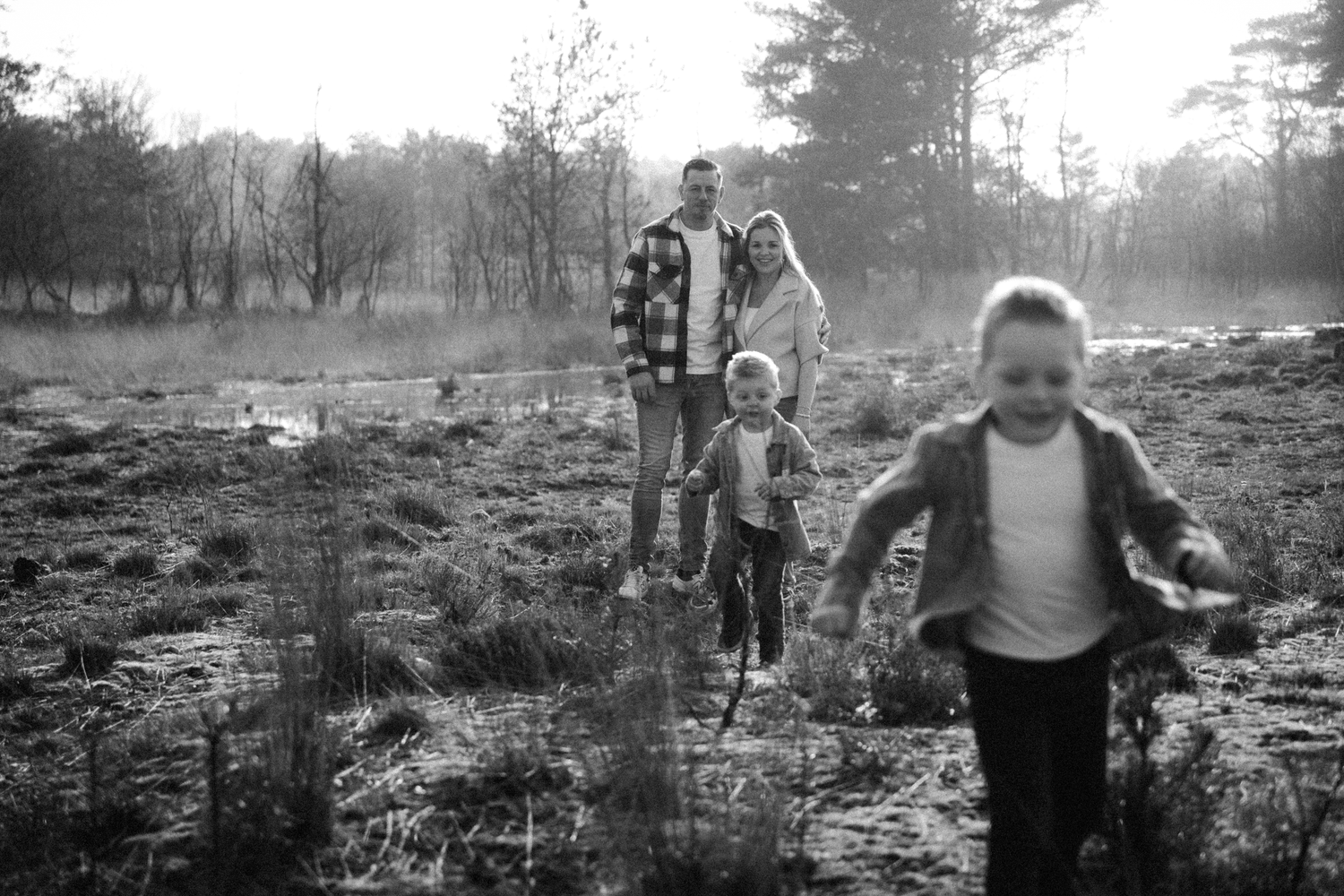 Black and white photo of a family walking together through a misty field on an autumn morning.