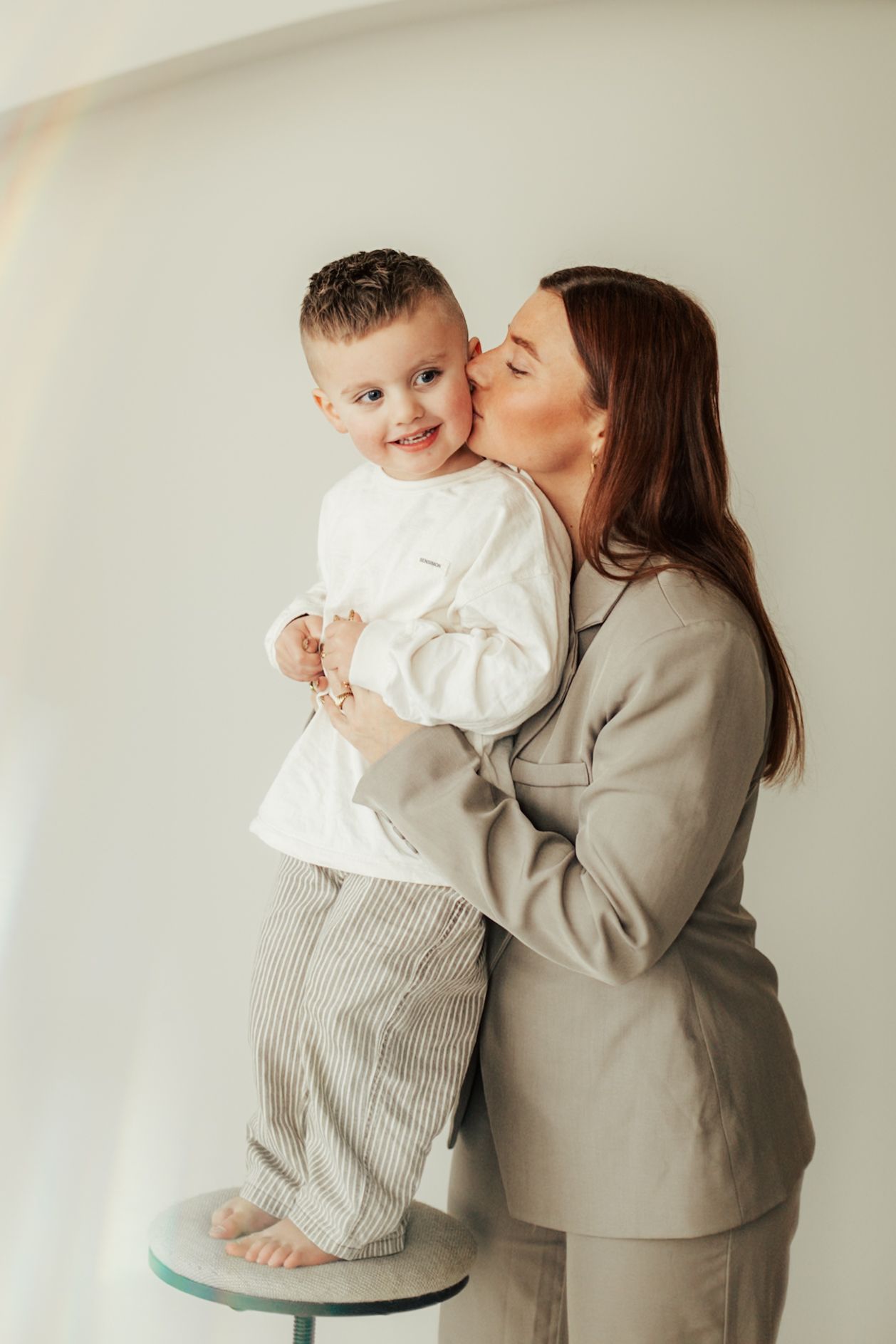 Sweet indoor portrait of parent and child in matching neutral tones.