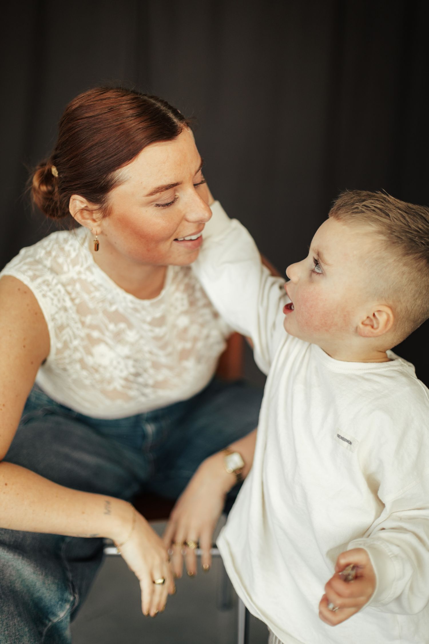 Intimate black and white portrait series of tender parent-child moments in white clothing.