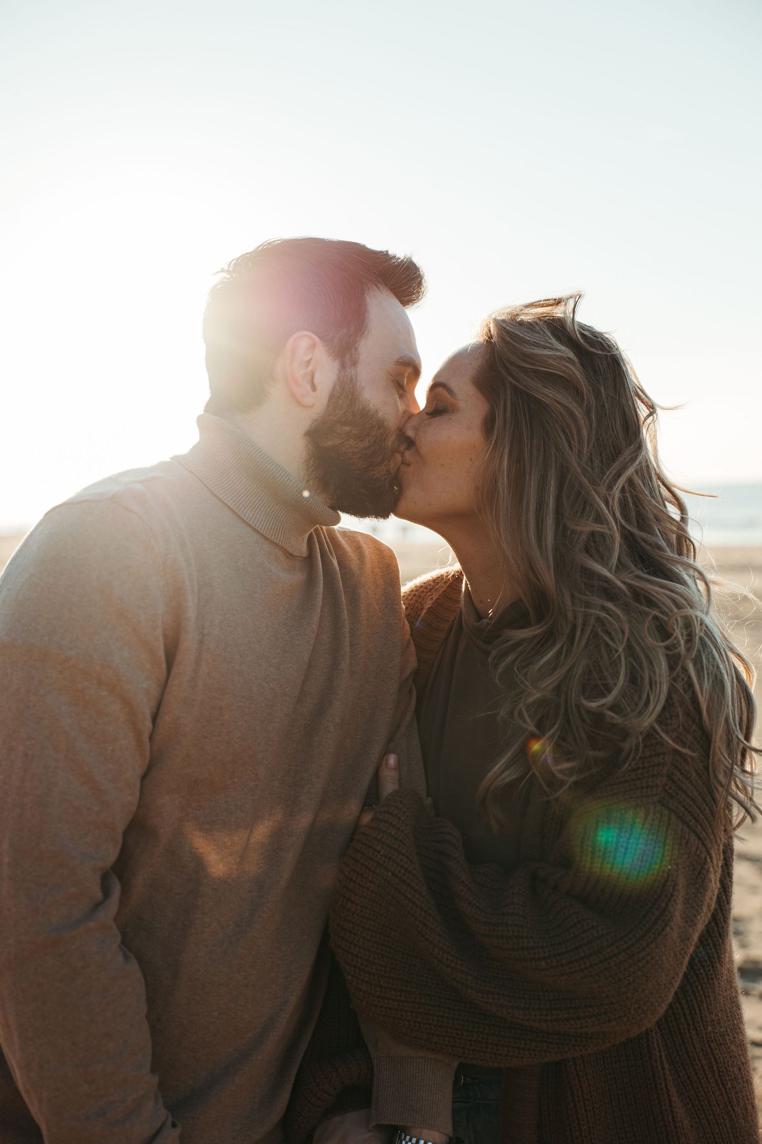 Intimate couple sharing a tender moment in warm sunlight on the beach.