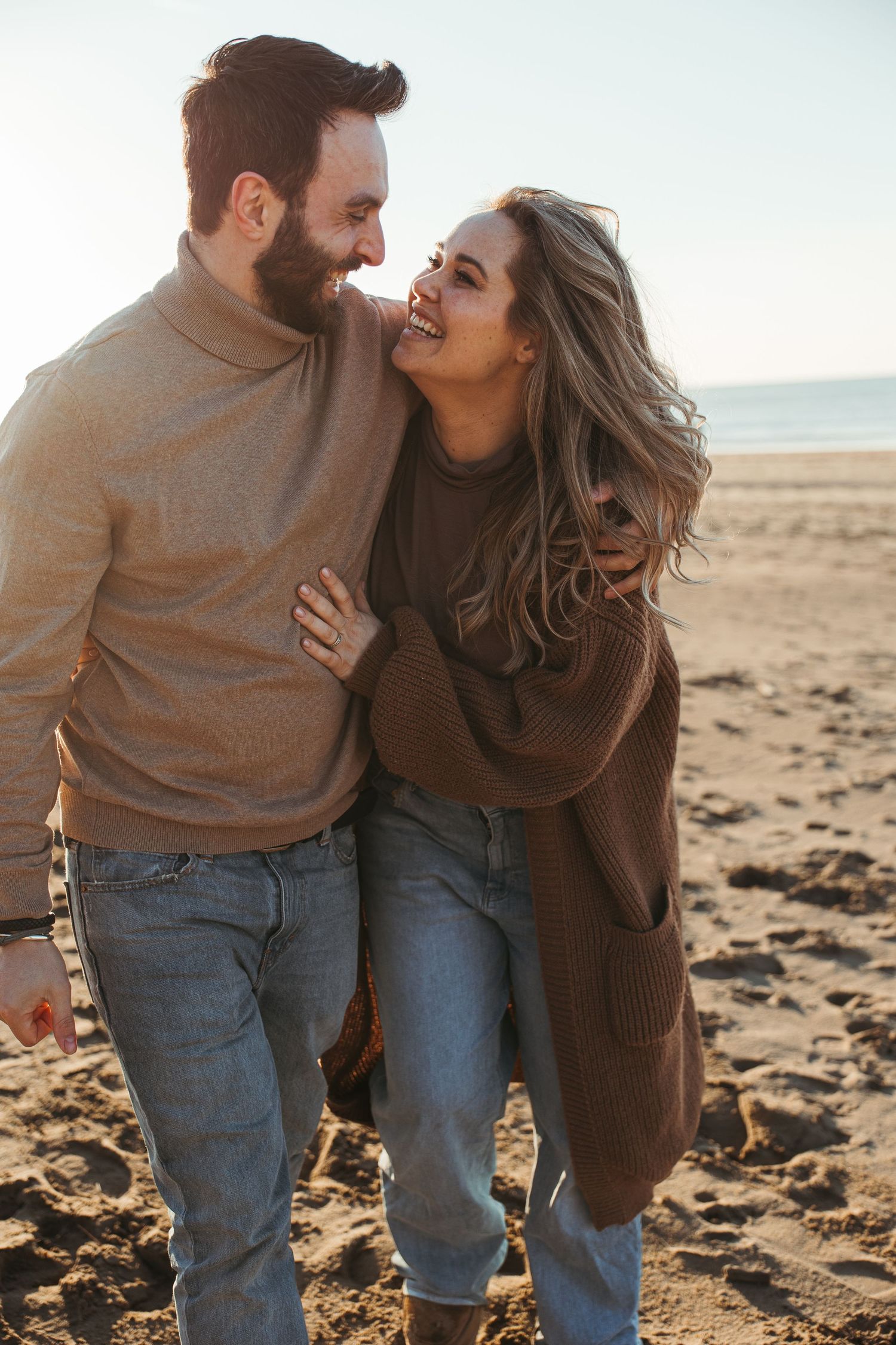 Couple in casual wear sharing intimate moments on a sunlit beach.