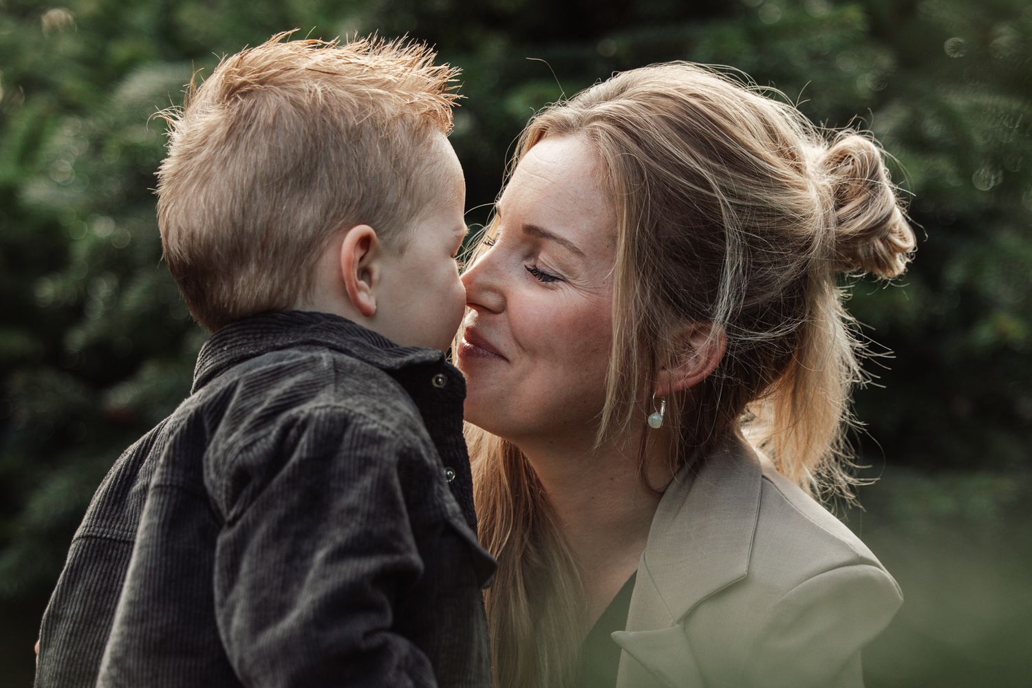 A tender family moment captured in a series of candid photos among evergreen trees.